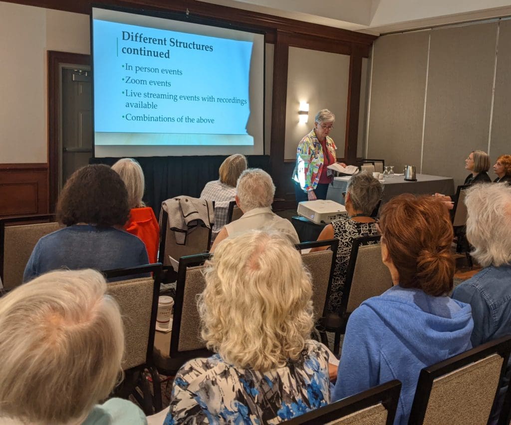 People sitting in a convention area watching a PowerPoint presentation